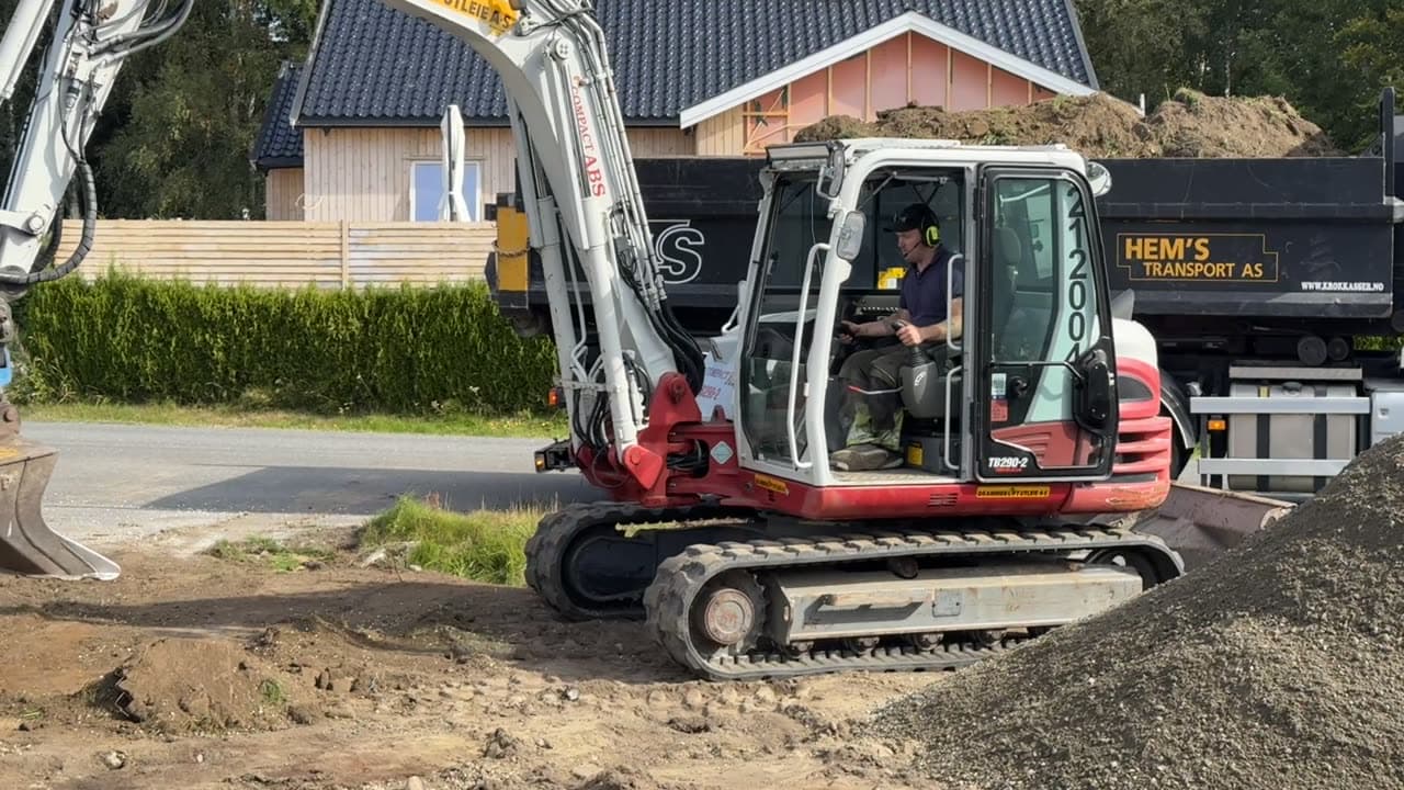 Gravemaskin i arbeid på en tomt ved et boligfelt